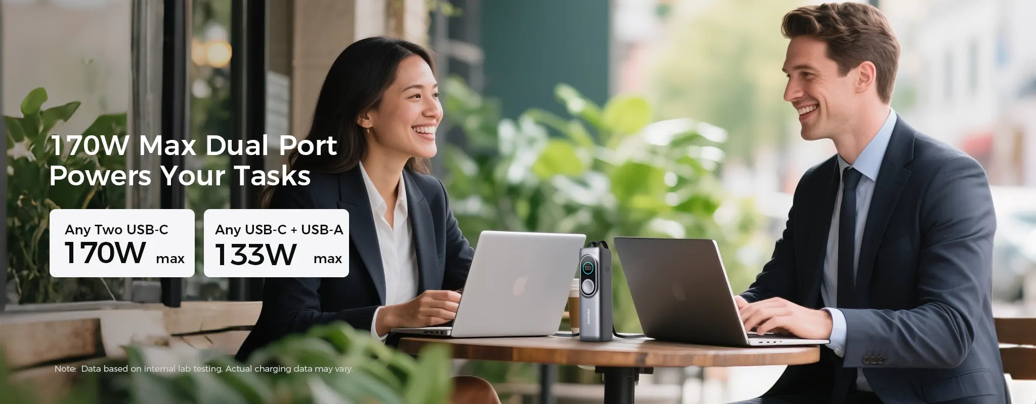 A professional man and woman working on MacBooks at an outdoor cafe, powered by a Rinecopo 170W max dual-port power bank. This high-speed portable charger supports up to 170W total output through any two USB-C ports, making it the perfect mobile energy solution for business meetings and digital nomads