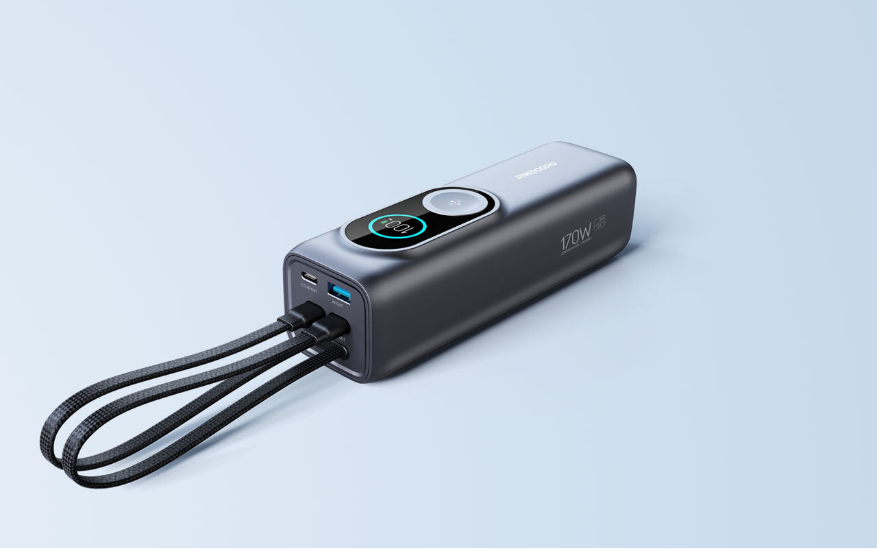 A sleek Rinecopo 170W fast charging power bank in space gray, set against a soft blue background. This high-capacity portable charger features dual integrated braided USB-C cables, a circular smart digital display, and multi-port output for charging laptops and smartphones simultaneously