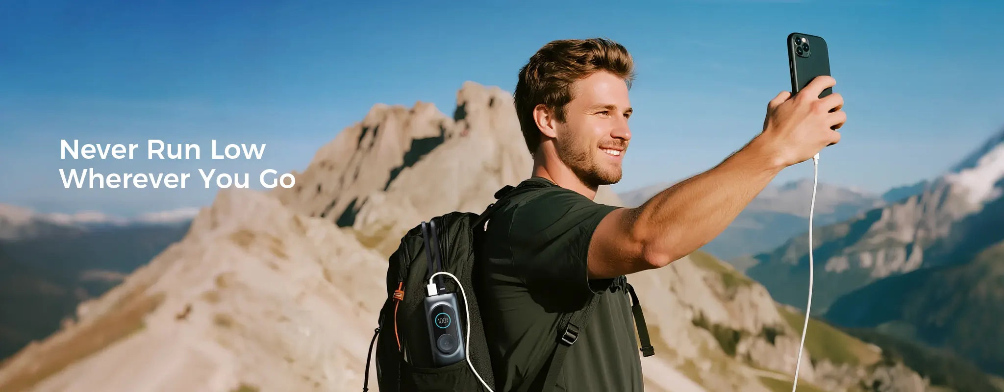 A traveler taking a selfie in the mountains while his smartphone is charged by a Rinecopo portable power bank stored in his backpack side pocket. This high-capacity external battery is an essential outdoor gadget for hikers and travel vloggers to stay powered anywhere