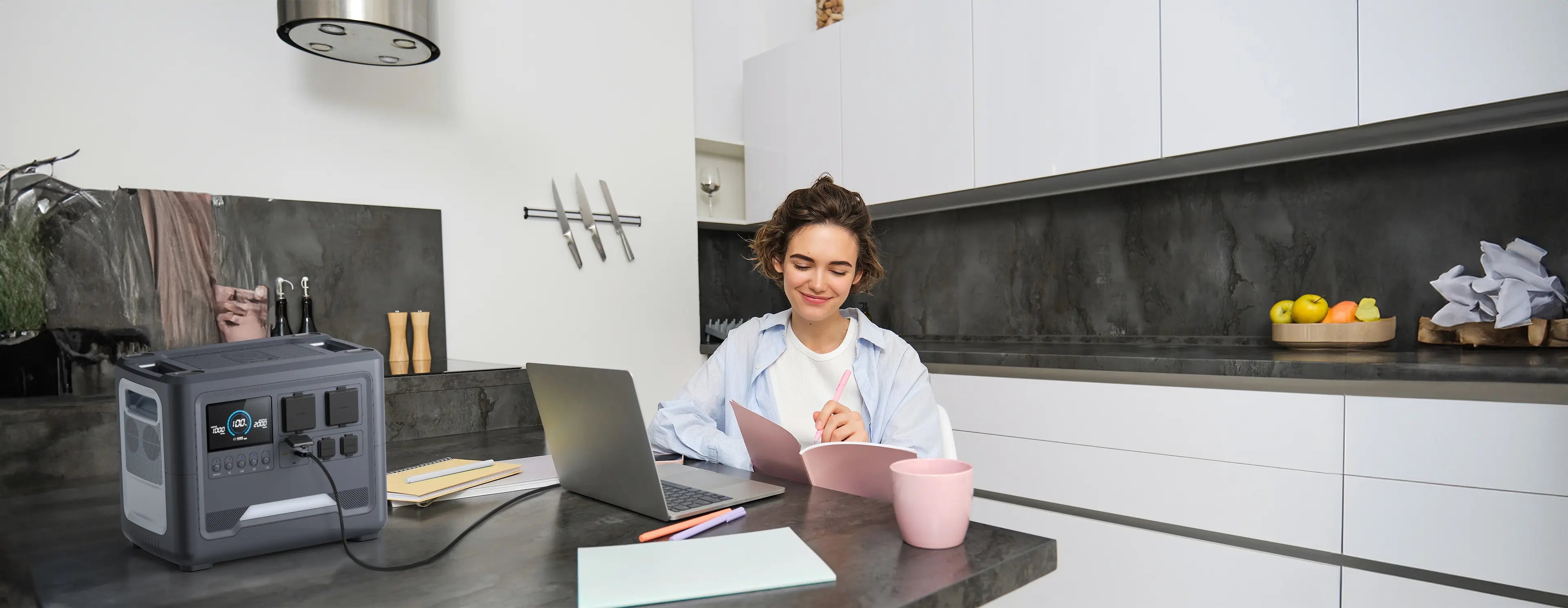 A woman working on her laptop in a modern kitchen powered by a Rinecopo portable power station. This reliable energy backup functions as a home UPS, ensuring an uninterrupted power supply for your workstation, MacBook, and home office setup during blackouts.