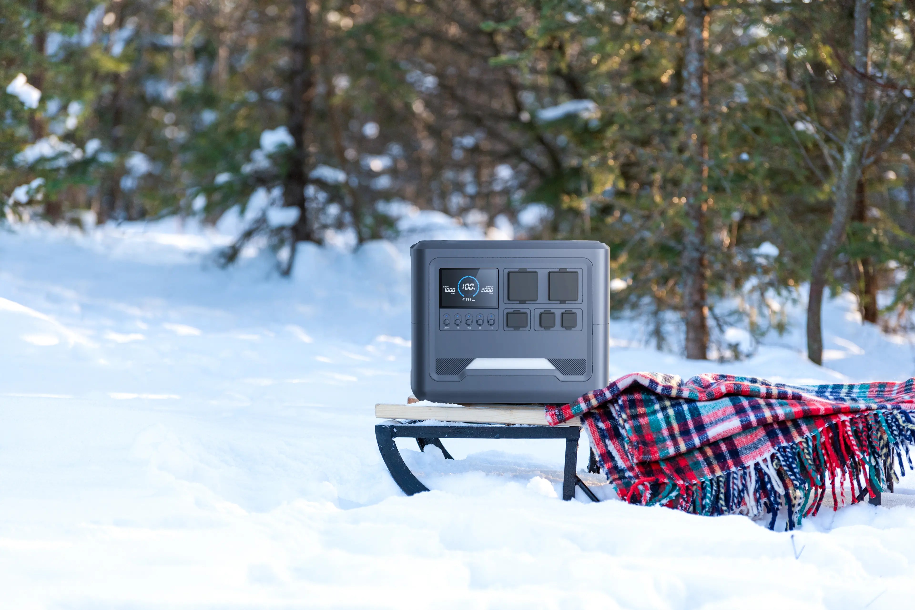 A Rinecopo portable power station placed on a wooden sled in a snowy winter forest. This high-capacity solar generator is designed for extreme weather performance, providing reliable backup power for winter camping, ice fishing, and cold-weather outdoor adventures