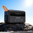 RINECOPO compact 300W power generator sitting on rugged rocks under the sun, delivering reliable on-the-go electricity for diverse daily and outdoor needs