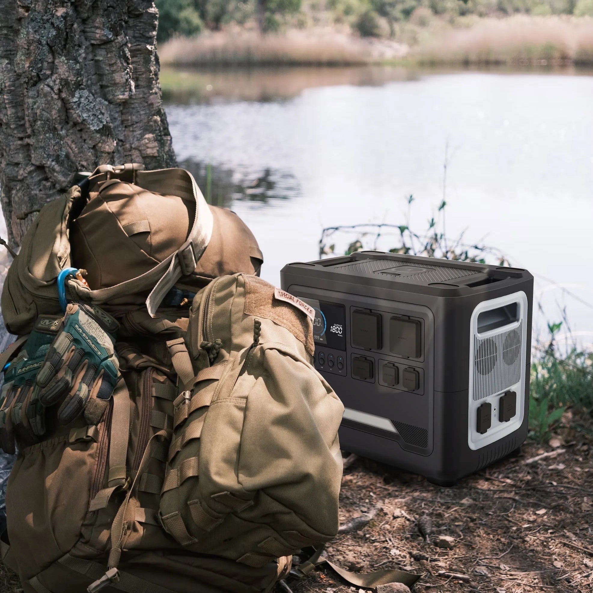 RINECOPO portable power station sitting next to a tactical backpack by a lake, providing reliable off-grid power for outdoor fishing and camping trips